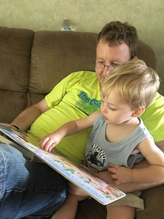 My son playing with a slider in a book as he sits on my lap.